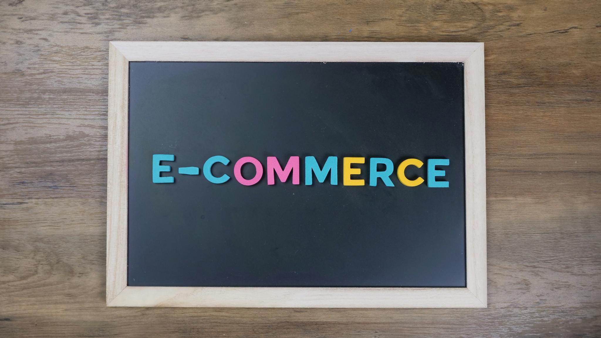 Colorful letters spelling 'e-commerce' on a wooden framed blackboard.